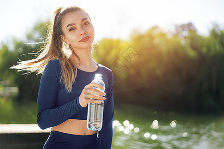 在公园穿蓝色运动衣饮用水的年轻美容女子肖像 照片来自女士运动员青少年女性成人口渴青年脱水女孩黑发图片