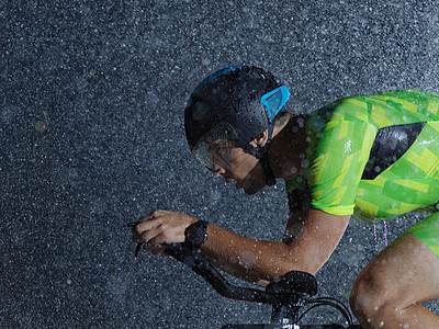 下雨之夜骑自行车的三重运动员速度耐力训练钢铁侠活力赛车手头盔男人铁人竞赛图片