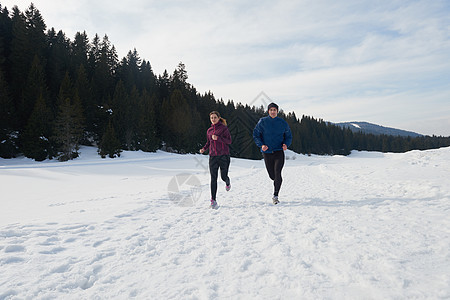 在雪地上在外面慢跑的情侣赛跑者阳光运动夹克公园训练山脉晴天女士活动图片