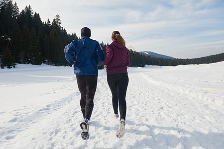 在雪地上在外面慢跑的情侣公园运动员夹克阳光山脉跑步者衣服训练晴天跑步图片