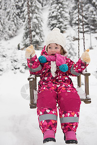 小女孩在雪寒冬日 在公园摇摆快乐女性乐趣孩子女儿帽子幸福微笑喜悦闲暇图片