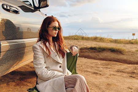 坐在田地椅子上的妇女 在汽车收成附近戴深墨镜倾斜天空女性短裤太阳镜假期摄影旅行成人阳光图片