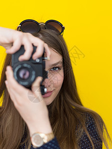 年轻女孩在反光相机上拍照黑色工作室摄影师微笑黄色摄影记者女性成人工作图片