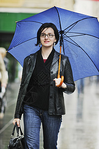 妇女带着雨伞在街上流浪季节天气蓝色夹克街道雨量下雨风暴购物城市图片
