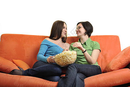 女朋友吃爆米花 在家看电视牛仔裤黑发电影友谊食物微笑女性电视长椅窗帘图片