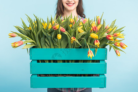 紧贴着亮木箱 蓝色背景有黄色的郁金香花瓣花朵植物女士地面明信片花束叶子花瓶礼物图片