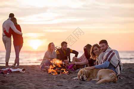 在海滩日落时和朋友共度欢乐的情侣幸福朋友们潮人沙滩旅行营火男人休闲女性派对图片