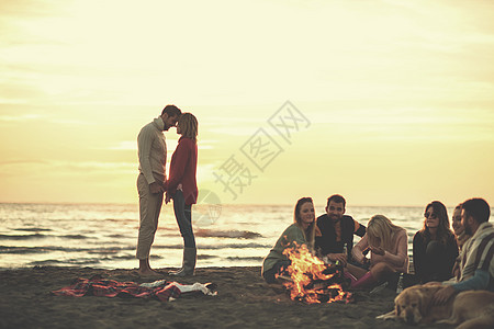 在海滩日落时和朋友共度欢乐的情侣乐趣快乐潮人旅行衣服营火沙滩火焰幸福城市图片