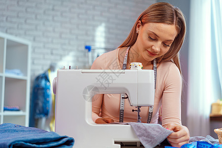 从事纺织厂缝纫机的年轻女裁缝者机器设计师缝纫女士爱好工作室纺织品裙子女性职场成人高清图片素材