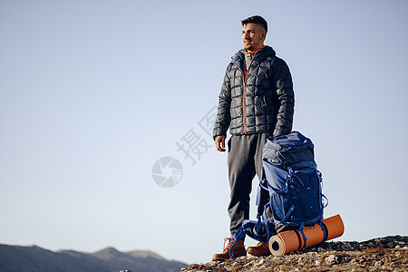 在山顶站立的徒步旅行设备中的男性背包男活动自由高度耐力男人顶峰天空爬坡农村旅游图片