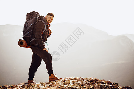 在山顶站立的徒步旅行设备中的男性背包男高度运动岩石活动男人农村地平线耐力冒险顶峰图片