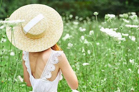 妇女穿着帽子 自然的鲜花散步休闲生活方式草地微笑金发晴天自由享受公园阳光太阳裙子图片