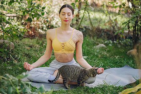 在夏日院子里训练猫的可爱女孩图片