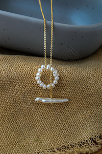 白珍珠首饰时尚摄影 白珍珠项链时尚摄影 项链呈现在棕色麻布上制品白色产品陶瓷配饰礼物女性蓝色织物静物图片