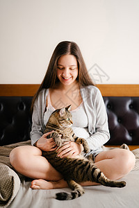 与猫坐在床上的孕妇图片