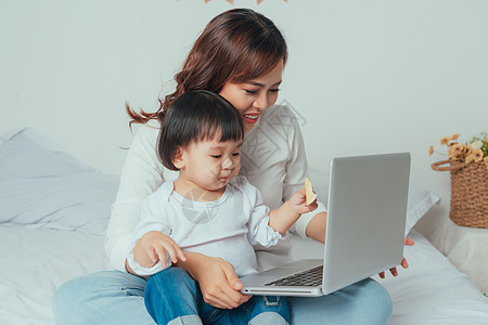 与使用无线技术的年轻母亲的女儿在一起母性父母互联网童年电脑婴儿房间家庭女性早餐图片
