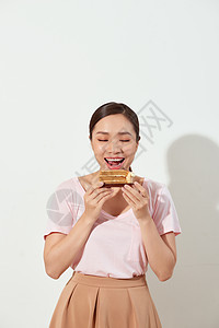 快乐的亚洲年轻女孩拿着一块美味的蛋糕 在白色背景中开心地笑着图片