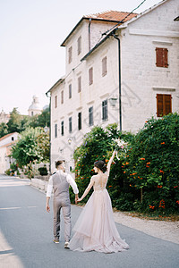 新娘和新郎走在街上 走过旧楼图片