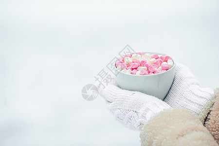 女性手用白色和粉色棉花糖握着白咖啡杯蓝色陶瓷制品季节围巾手指杯子早餐牛奶溜冰场图片
