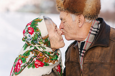 愉快的年长夫妇画象 老妇人重重地亲吻她的丈夫 老夫妇在冬天的时候在公园散步 幸福的家庭 金婚女士男人退休婚礼季节微笑皱纹皮肤长老图片