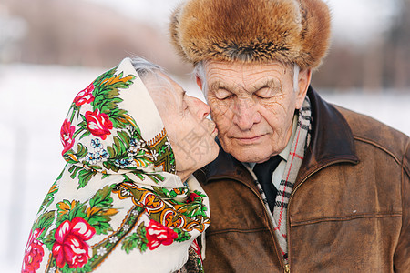 愉快的年长夫妇画象 老妇人重重地亲吻她的丈夫 老夫妇在冬天的时候在公园散步 幸福的家庭 金婚皱纹老年女性长老疾病男人婚礼退休老年图片