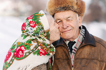 愉快的年长夫妇画象 老妇人重重地亲吻她的丈夫 老夫妇在冬天的时候在公园散步 幸福的家庭 金婚疾病乐趣婚礼老年人皱纹男性微笑成人长图片