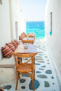 米科诺斯岛一家典型的希腊户外咖啡馆的带枕头的长椅 享有基克拉迪群岛的壮丽海景鹅卵石咖啡店村庄石头胡同建筑旅游天空街道房子图片