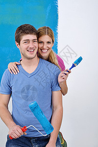 幸福的一对情侣在新家的油漆墙刷子蓝色滚筒男性男人女性风格喜悦成人房子图片