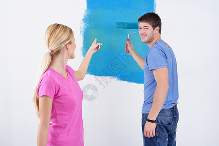 幸福的一对情侣在新家的油漆墙蓝色风格喜悦男性男人房子装饰滚筒刷子家庭图片