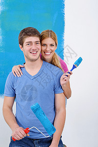幸福的一对情侣在新家的油漆墙成人刷子女士蓝色房子微笑女孩风格滚筒乐趣图片