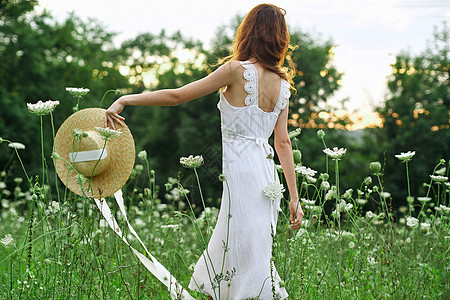 穿白色衣服的妇女开着鲜花自由走新鲜空气晴天女孩享受微笑草地自由女性太阳裙子公园图片