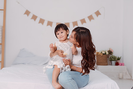 快乐的年轻女子和可爱的小孩玩耍 一岁女孩 在床上放松父母感情微笑女儿女性拥抱家庭喜悦成人卧室图片