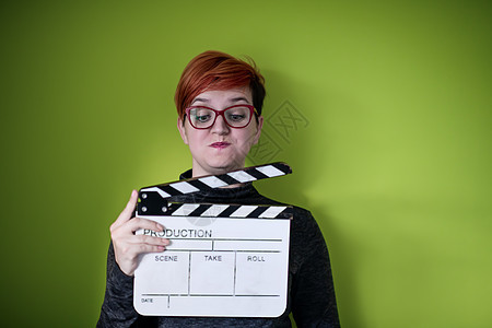 女性在绿色背景下拍摄电影拍手相机工作室隔板教育视频娱乐粉笔闲暇钥匙木板图片