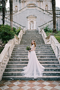 穿着长裙子的新娘站着半包装在一栋旧楼附近的石脚上高清图片