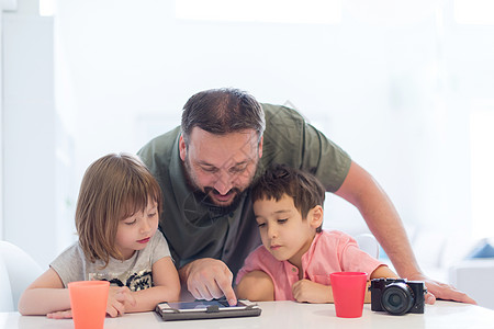 在家的单身父亲 有两个孩子在平板电脑上玩游戏技术儿子药片微笑成人兄弟爸爸女孩房间父母图片