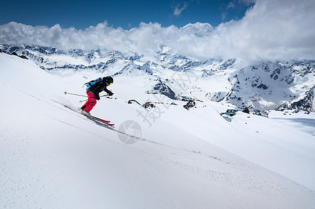 在高山上滑雪 与山顶和云层相对抗的女子滑雪图片