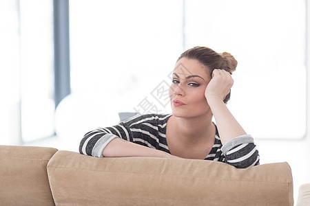 一位坐在沙发上的年轻美女的肖像女士白色女性微笑女孩姿势成人房间闲暇冒充图片
