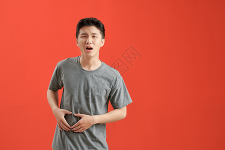 年轻的亚洲男子身穿白色短袖圆领汗衫 患有胃痛和痛苦的疾病概念图片