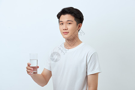 穿着白色T恤的快乐男人手里握着一杯水图片
