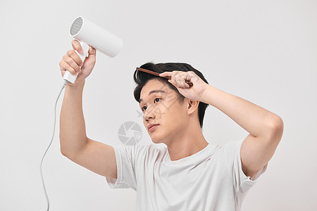 年轻的亚洲男子手持吹风机和梳子 在白色背景上制造新发型男生造型工具理发师创造力男人头发造型师烘干烘干机图片