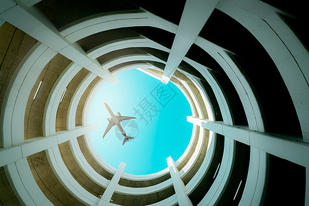 货运飞机底视图多层停车场大楼 飞机在大楼上方飞行 航空物流 航空和旅游业务 螺旋曲线建筑体系结构 航空公司业务 旅游交通背景
