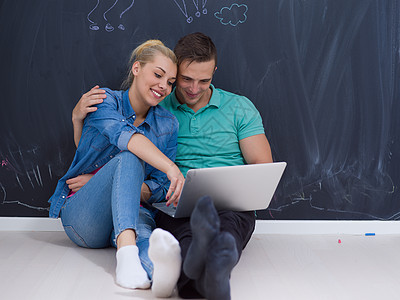 一对夫妇在灰色黑板前使用笔记本电脑男人女孩男性女士快乐工作室女性微笑男朋友成人图片