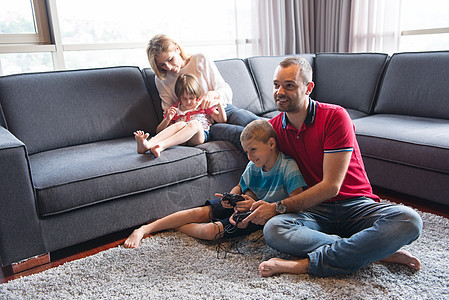 快乐家庭玩电子游戏女士娱乐控制器男生母亲技术男人竞争游戏童年图片