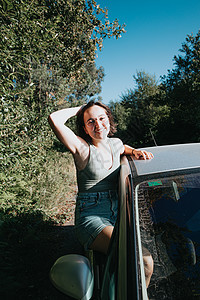 美丽的白人年轻时髦女性在窗外的一次汽车旅行中摆姿势 范生活的生活方式 旅行和幸福的概念 日落日的眼镜假期车辆职业司机成人自由商务图片