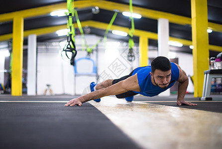 年轻男子做俯卧撑健身房培训师重量力量男性俱乐部身体专注建筑健美图片
