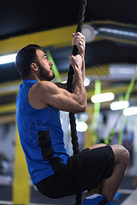 男人在攀爬绳索男性火车运动员健身房肌肉力量体操运动装健美培训师图片