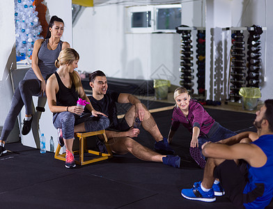 年轻运动员坐在地板上 放松着休息女士训练力量活动身体肌肉友谊健身房运动闲暇图片