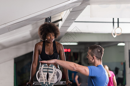 黑人妇女与教练一起做平行酒吧锻炼体操培训师运动装二头肌身体肌肉重量水平运动员运动图片