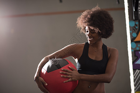 黑黑妇女携带交叉球健身房闲暇活动肌肉药品重量运动装俱乐部女孩教练图片