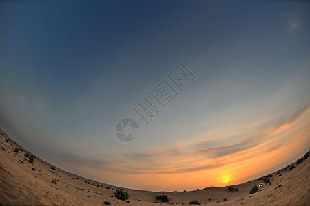 沙漠中美丽的日落蓝色场景爬坡阴影橙子环境荒野天空地平线太阳图片